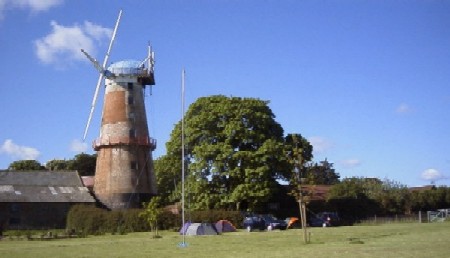 Mill with tents at base and mast in foreground
