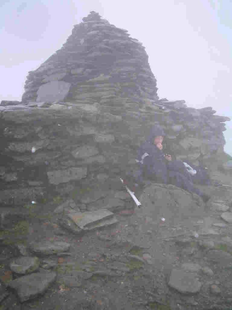 Jimmy shelters by the summit cairn