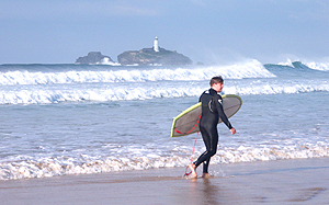 A surfer running across the beach