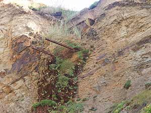 Rails and a mining trolley protruding from the clifftop, Gwithian Towans