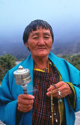 A Budhist lady with a portable prayer wheel and a rosary