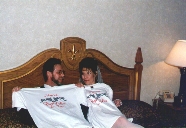 Roy and Paula in bed showing off their T-shirts