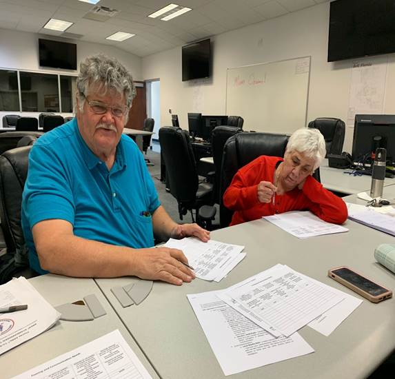 A person and person sitting at a table with papers

Description automatically generated