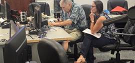 A person and person sitting at a desk

Description automatically generated