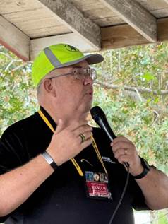 A person wearing a yellow hat and holding a microphone

Description automatically generated