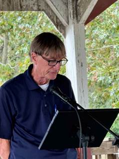 A person standing at a microphone

Description automatically generated