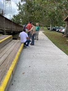 A group of people standing on a sidewalk

Description automatically generated