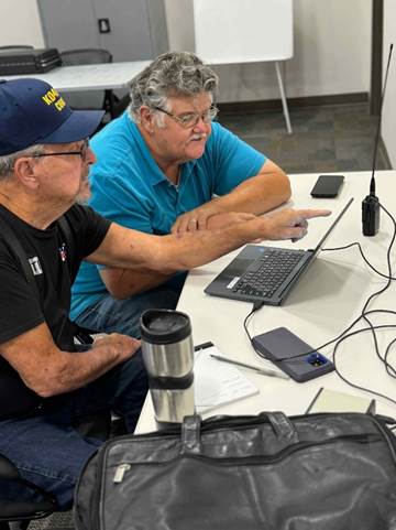 Two men sitting at a table looking at a computer